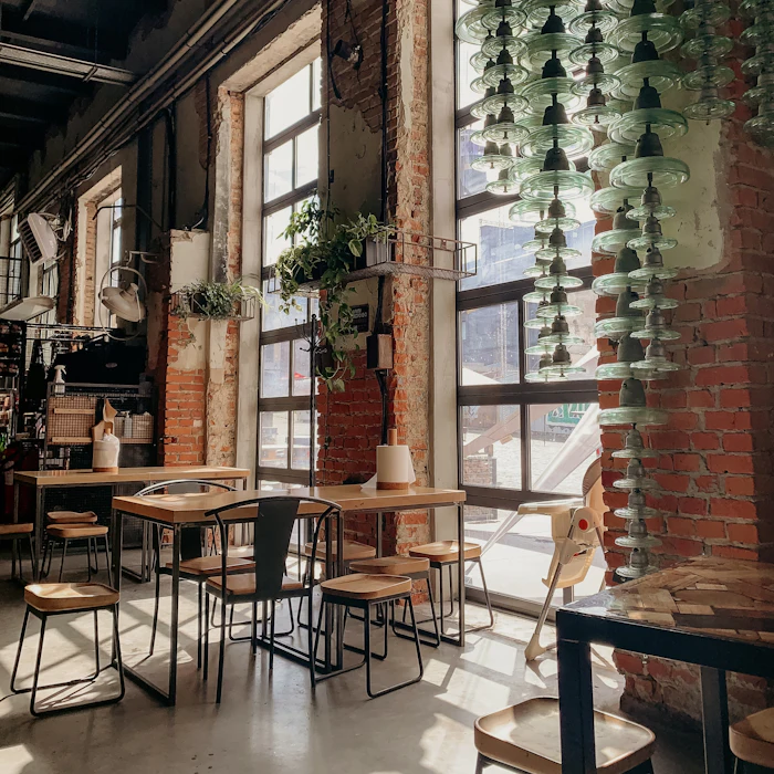 The café floor with tables, chairs and plants in morning light