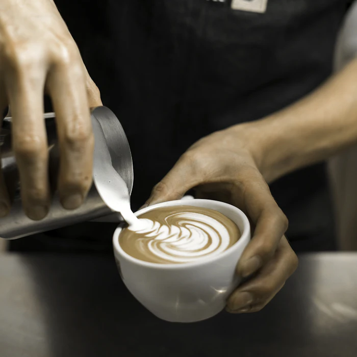 A barista pouring latte art into a cup